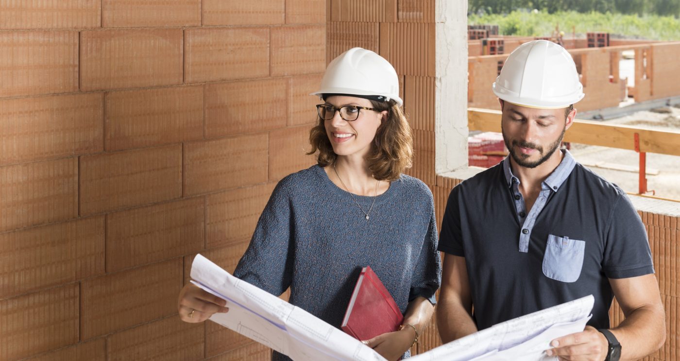 Male and female building professionals with technical drawing in new built construction