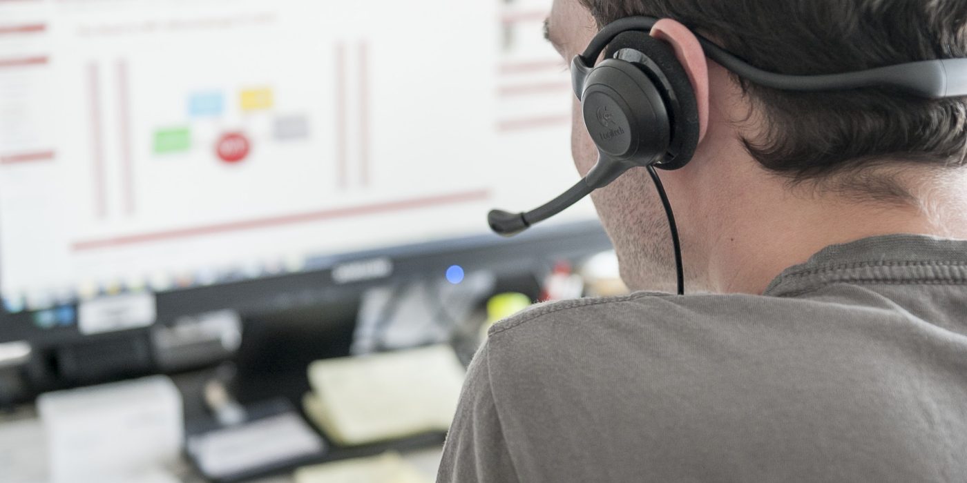 Young man sitting in front of computer screen with headset
