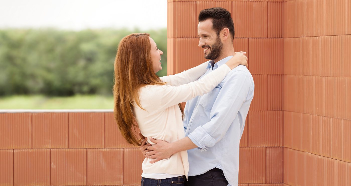 Man and woman celebrating their future home inside building shell