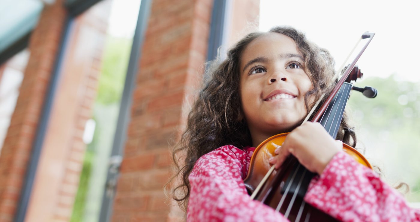 Girl embracing a violin inside a brick-lined building