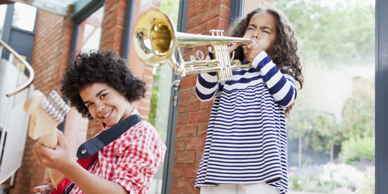Noisy kids playing electrical guitar and trumpet inside well insulated brick-built house