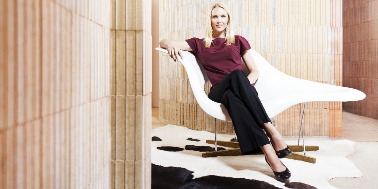 Woman sitting on "La Chaise" Eames chair in unfinished building