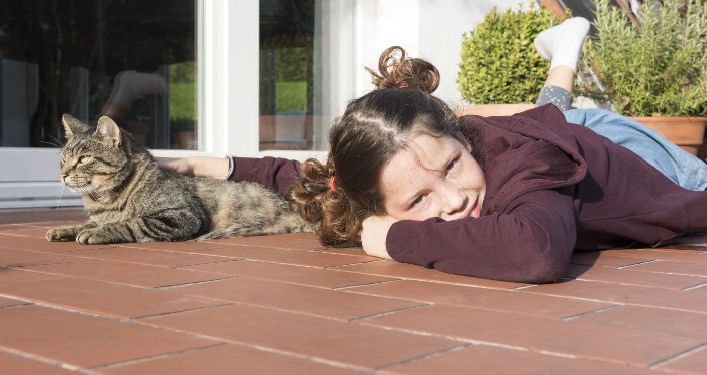 Girl with cat relaxing in the sun on the clay paved terrace